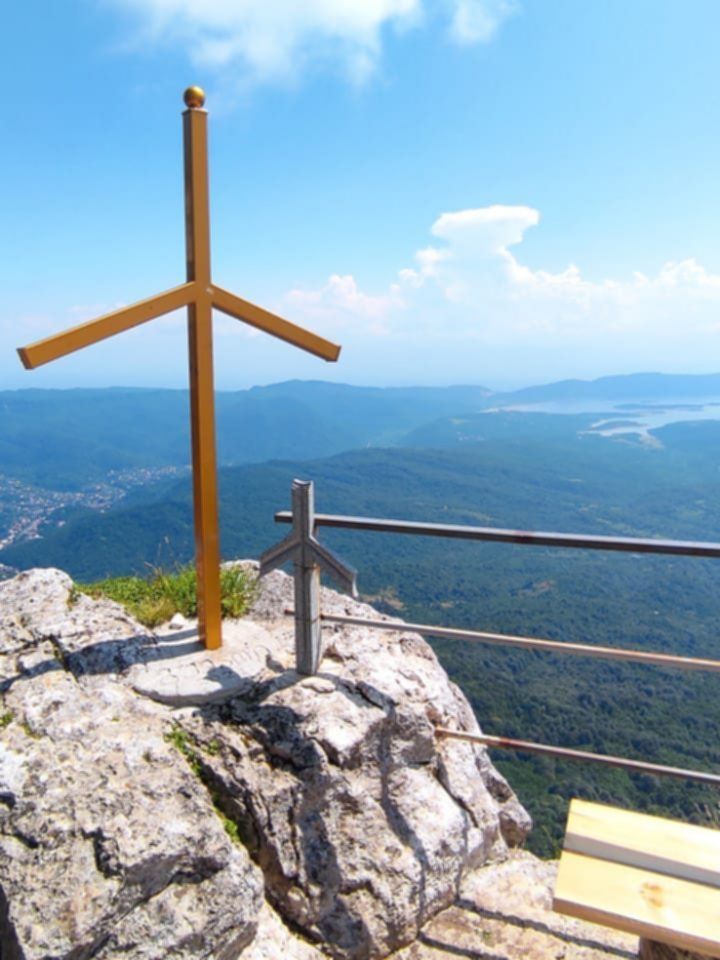 Widok z punktu 9 Jvari w Gruzji – dziewięć krzyży na skalnym tarasie widokowym oraz panorama zielonych wzgórz i jezior w oddali.