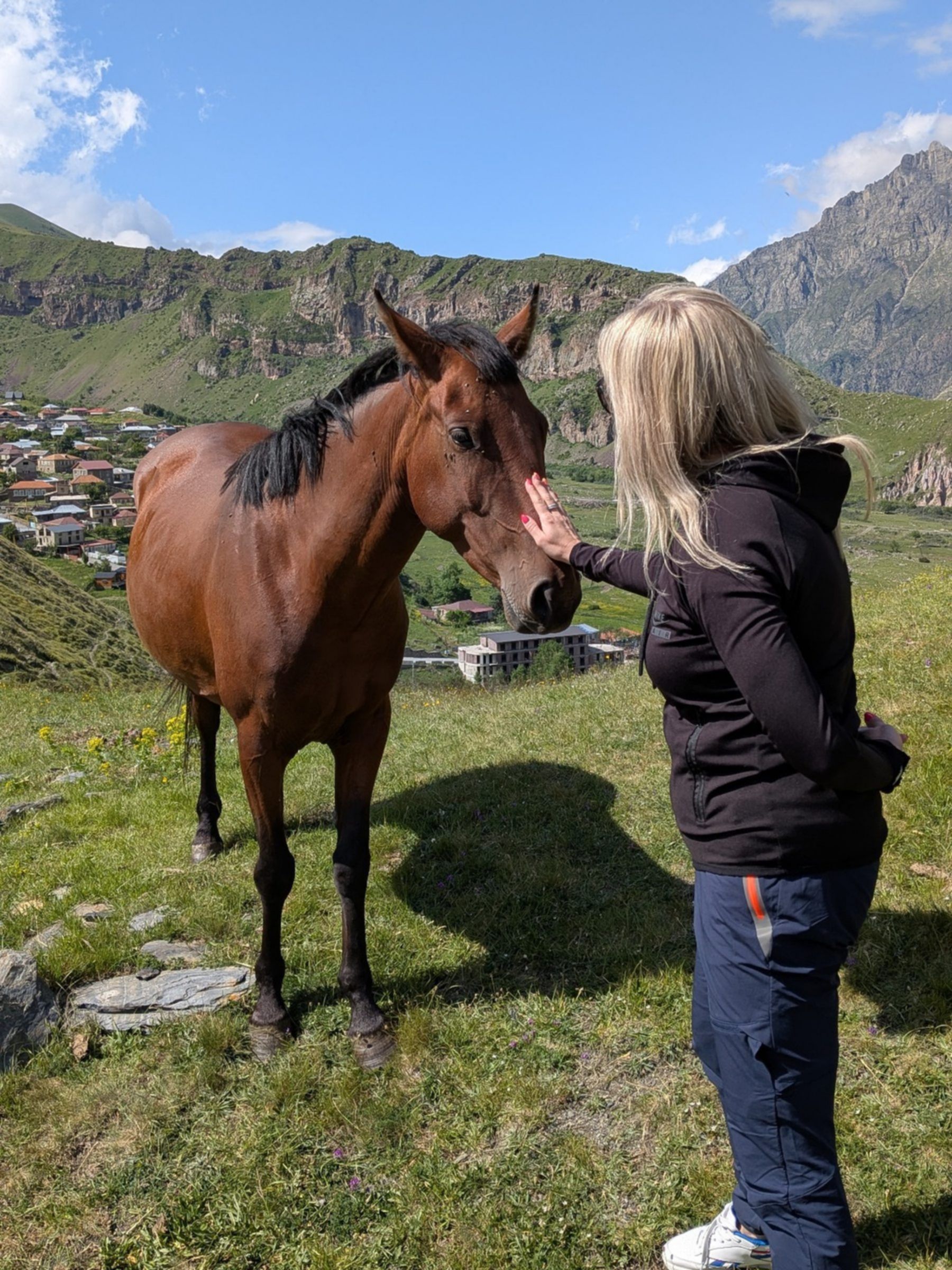 Turystka głaszcząca konia na górskiej łące w Gruzji, autentyczne doświadczenie podczas wyjazdu