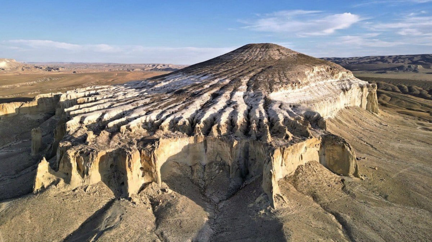 Monumentalna góra Szerkała w Kazachstanie przypominająca odwróconą misę, o wyraźnych żłobieniach erozyjnych.