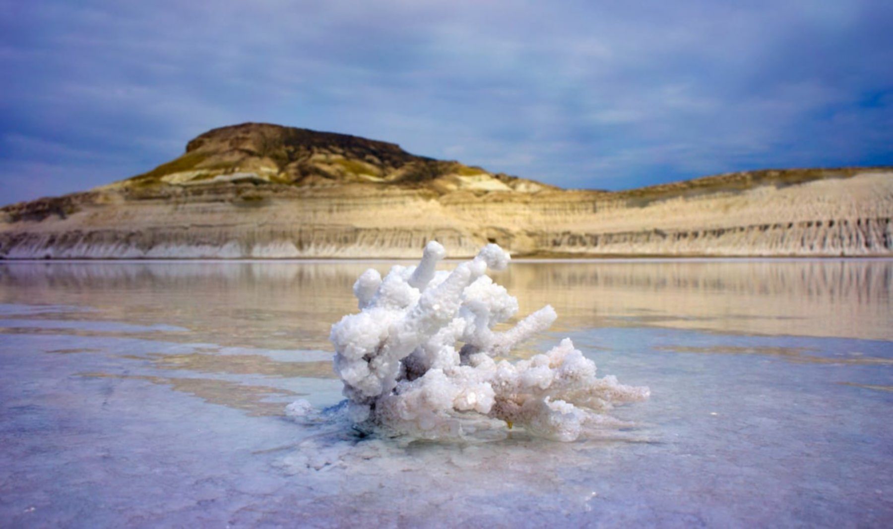 Solny krajobraz Tuzbaiyr z krystalicznymi strukturami soli unoszącymi się nad lustrzanym jeziorem.