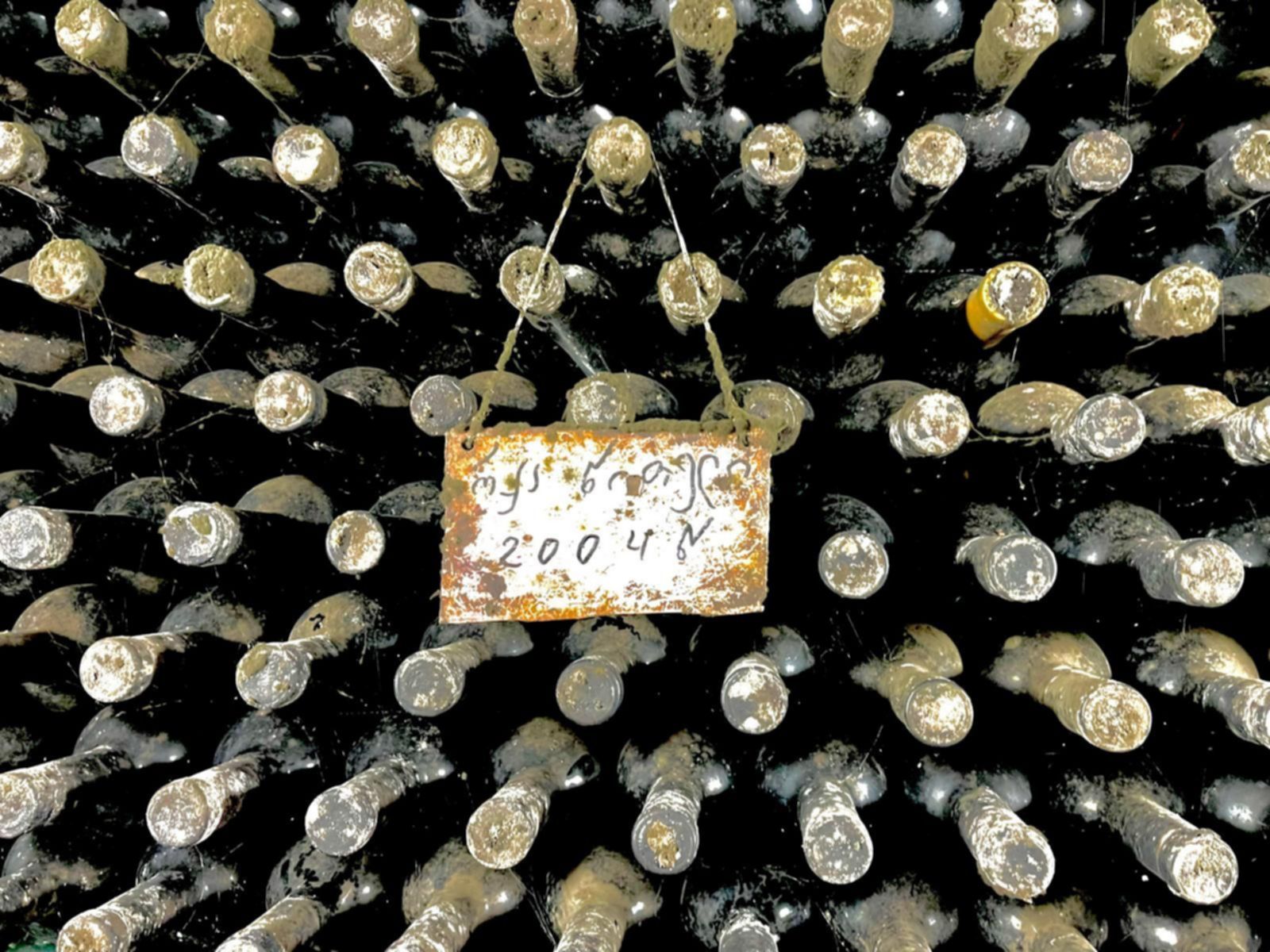 Tradycyjne gruzińskie wino leżakujące w butelkach w lokalnej piwnicy