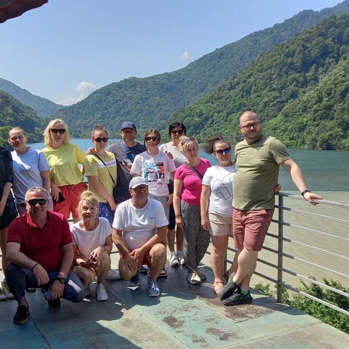 Grupa uczestników wyjazdu do Gruzji nad dwukolorową rzeką w górskim krajobrazie